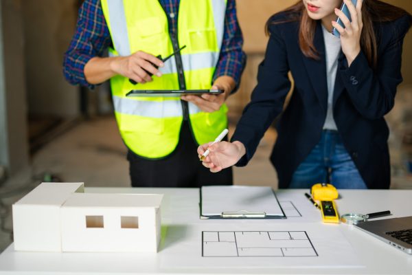 Creative architect projecting on the big drawings with architectural project at construction site at desk in modern office