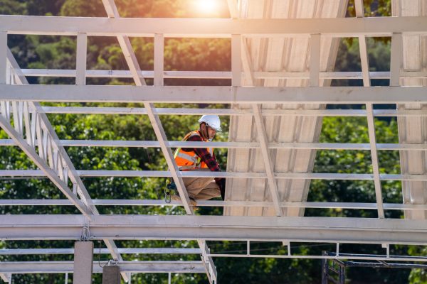 Roofer working in protective work wear gloves,Construction worker wearing safety harness working at high level in the construction site install new roof,metal roof.